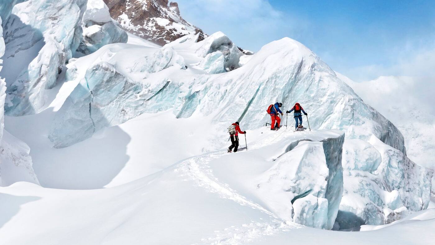 Die Gruppe vor einem imposanten Gletscherabbruch bei strahlend blauen Himmel.