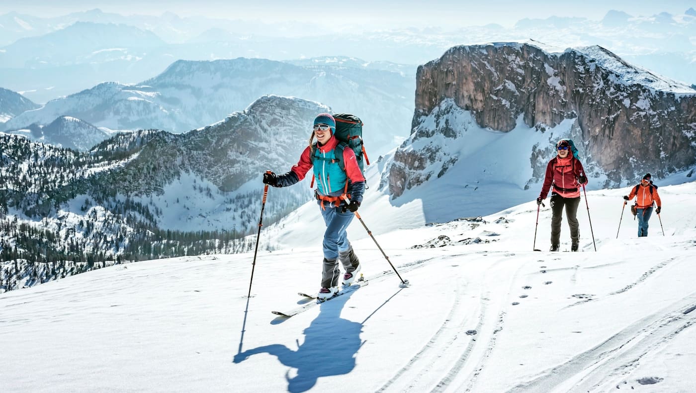 Sportler mit den Skiern am Weg zum Gipfel.