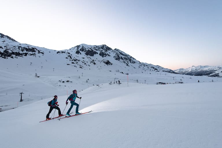 Skitourengeher auf der Skipiste am Abend