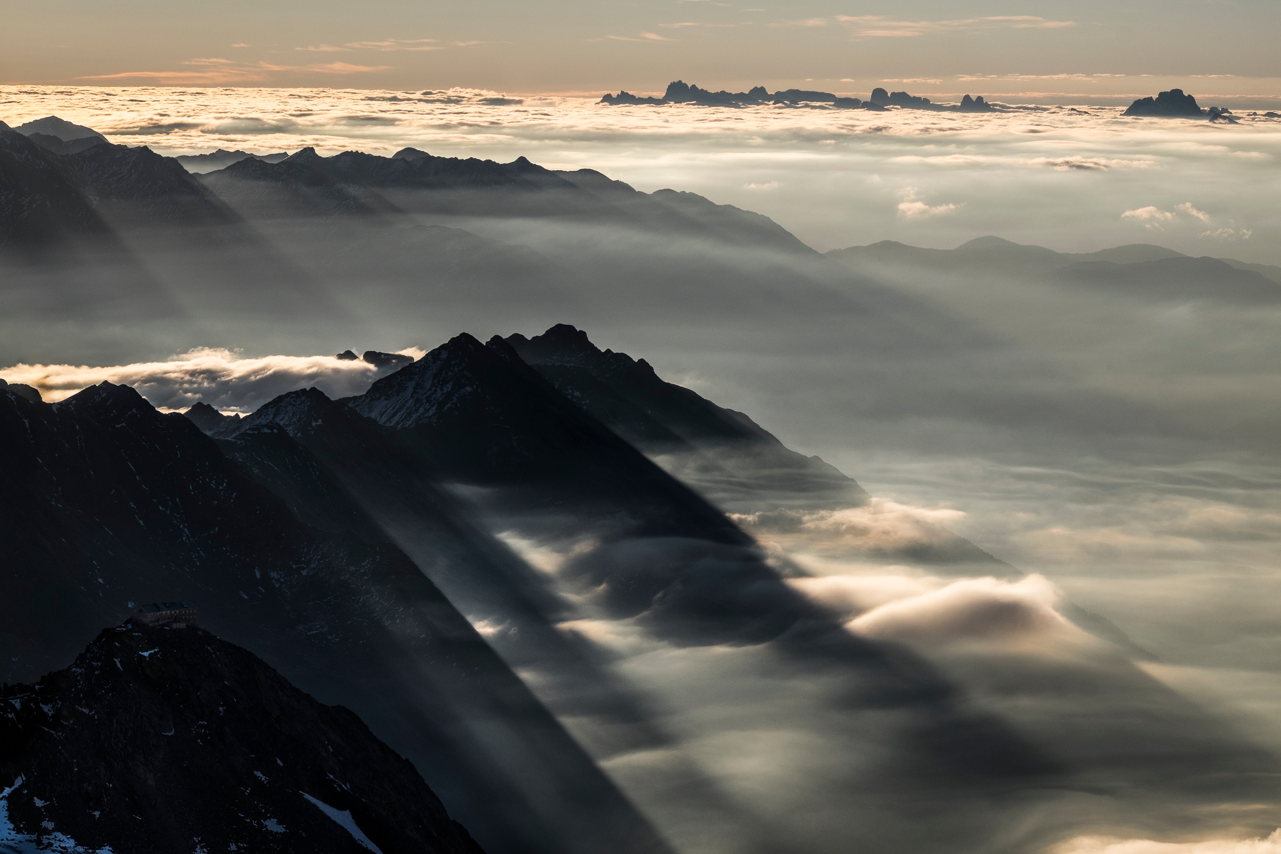 Das Nebelmeer aus Südtirol brandet an die südlichen Ausläufer der Stubaier Alpen. Im Vordergrund steht exponiert das Becherhaus, ganz hinten ragen die Spitzen der Dolomiten aus dem Nebel