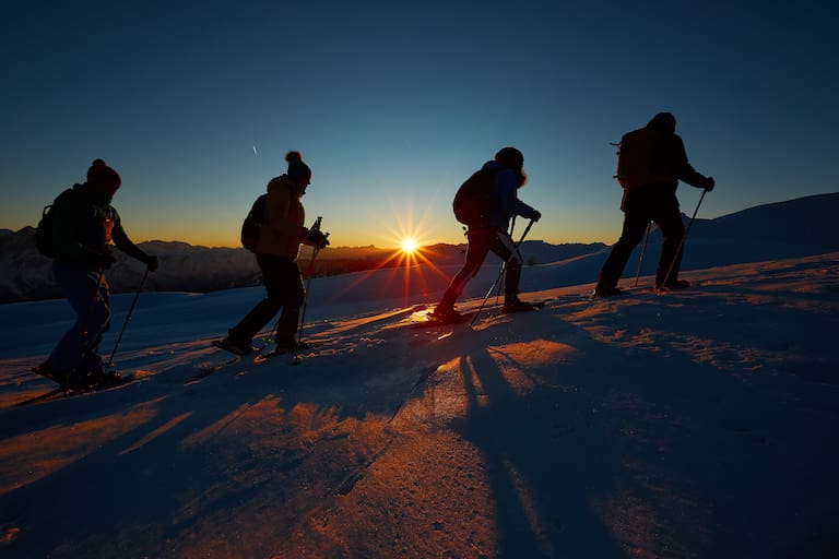 Eine Schneeschuhtour bei Sonnenuntergang stellt ein unvergessliches Erlebnis dar.