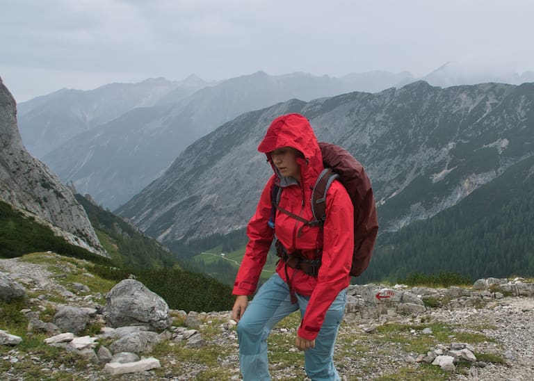 Bergsteiger mit roter Jacke bei schlechtem Wetter