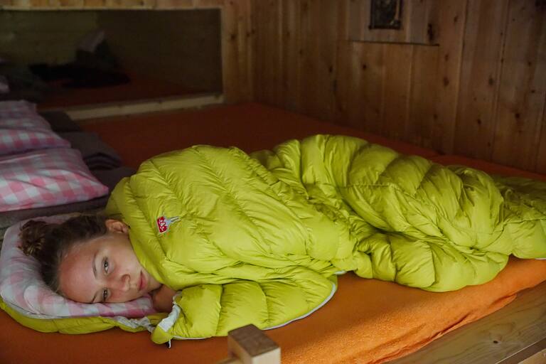 Mädchen in Schlafsack auf einer Berghütte