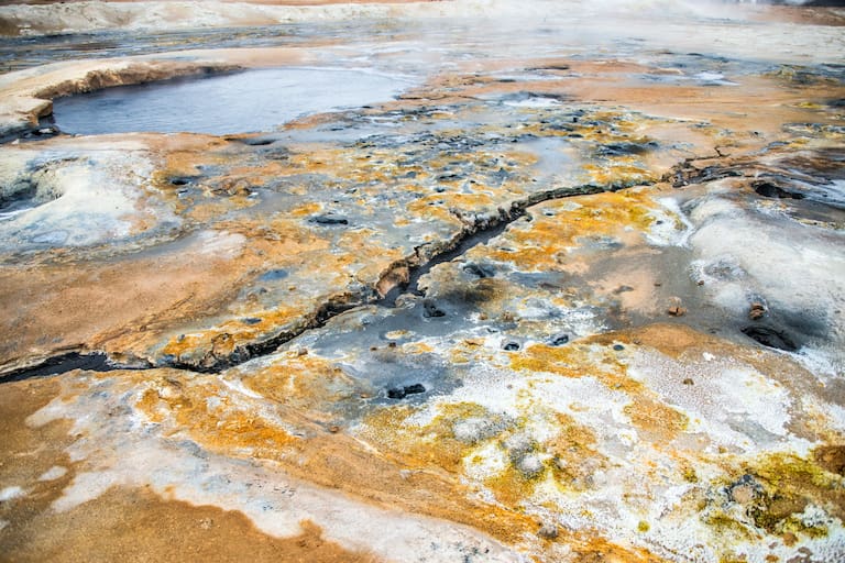 Gelb-Schwarzes Gestein mit Wasserbecken und kleinen Flüssen am Námafjall - Ort mit erhöhter vulkanischer Aktivität 