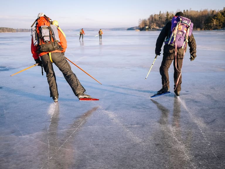 Zwei Nordic Skater mit Rucksäcken auf einem gefrorenen See nahe Uppsala 