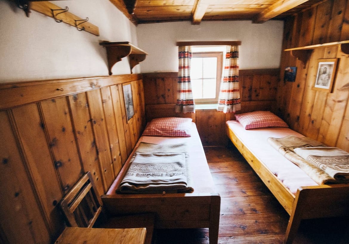 Die urigen Zimmer aus Zirbenholzmöbel mit klassisch rotkarierter Bettwäsche