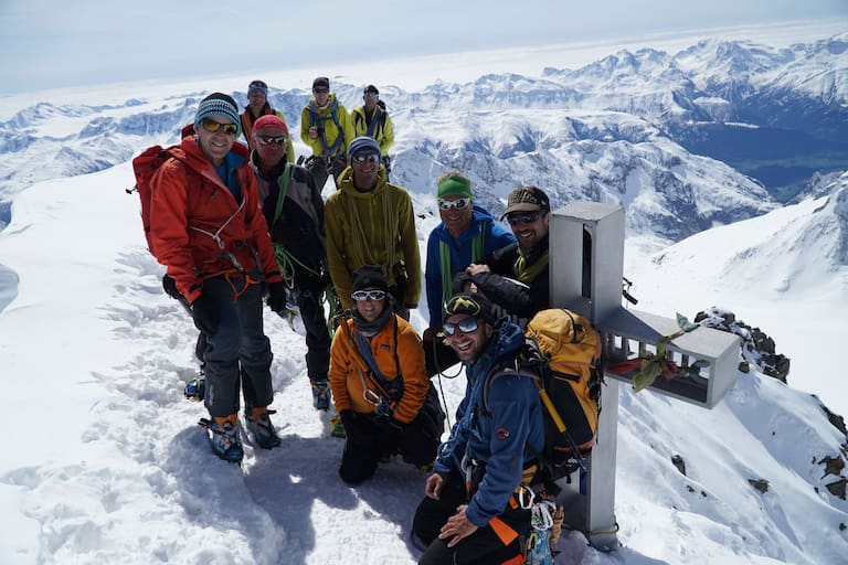 Bergführer mit Gruppe am Gipfel