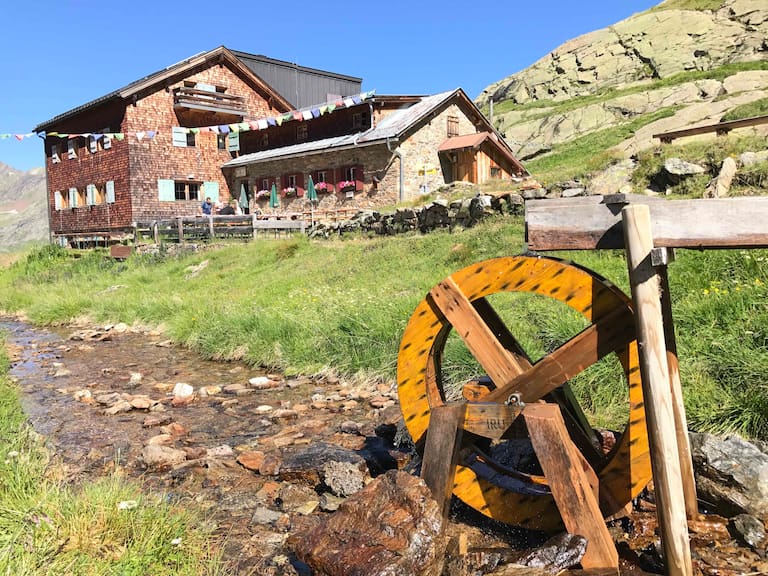 Viele Hütten gewinnen ihre Energie aus Kleinwasserkraftwerken. Symbolhaft mit diesem schönen Holzwasserrad vor der Edmund-Graf-Hütte im Verwall dargestellt. 