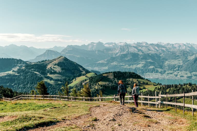 Zwei Wanderinnen auf der Rigi mit Bergen und Vierwaldstättersee im Hintergrund