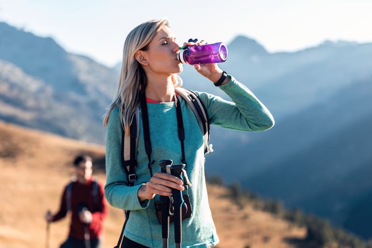 Mädchen trinkt Wasser am Berg