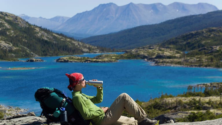 Trinkpause: Wanderin an einem Bergsee in Kanada