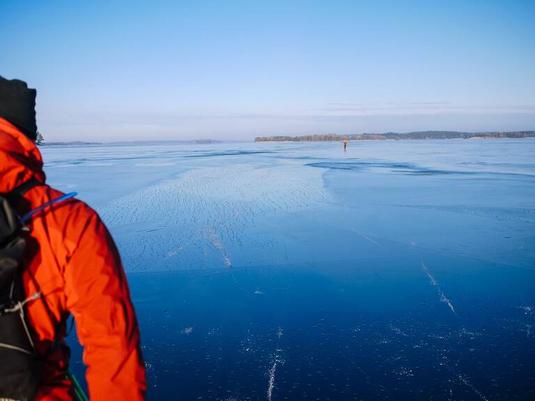 Blauer Himmel und blaues Eis in Schweden mit Anschnitt eines Nordic Skaters 