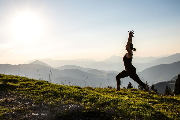 Eine Frau macht Yoga vor einer Bergkulisse.